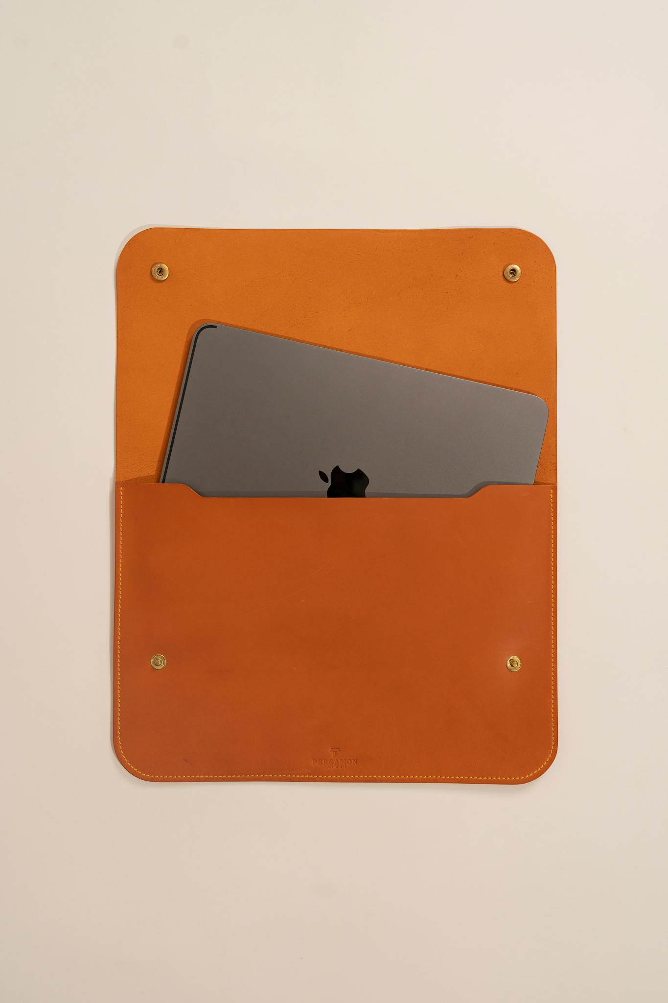 Leather laptop sleeve holding a device, shot with a front angle for minimal design appeal.